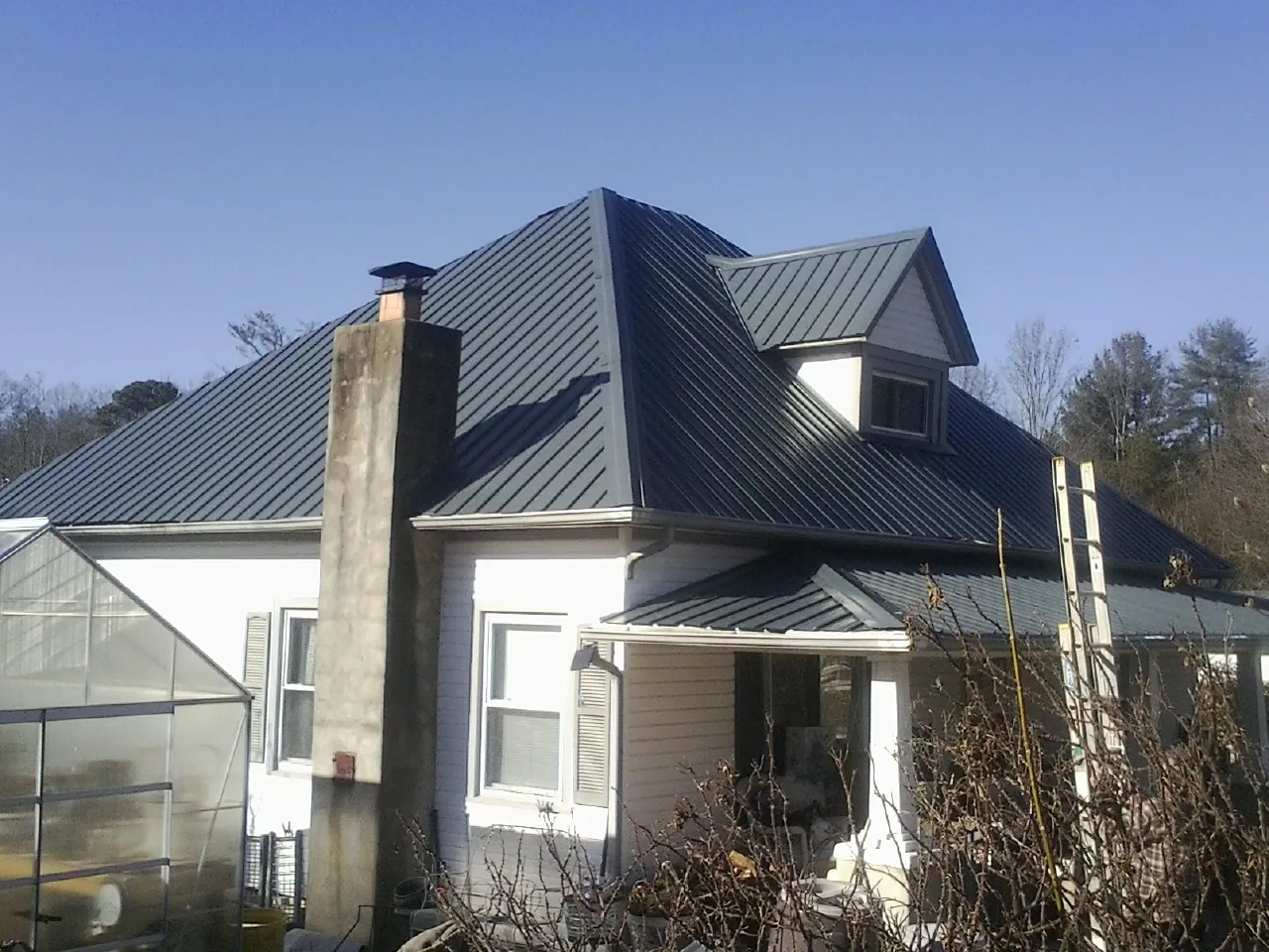 Dark blue standing seam metal roof on a white farmhouse with dormer — Slate & Tile Roof Repair by Roofing Brothers in Waukomis