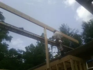 Carpenter setting a ridge beam over a new addition frame — Ice Dam Removal by Roofing Brothers in Waukomis