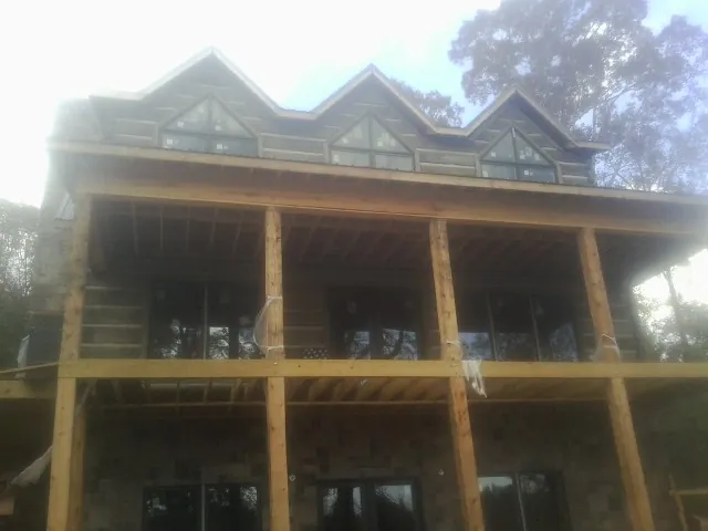 Dormers and porch framing on a large log home under construction — Roof Coating work by our crew in Waukomis