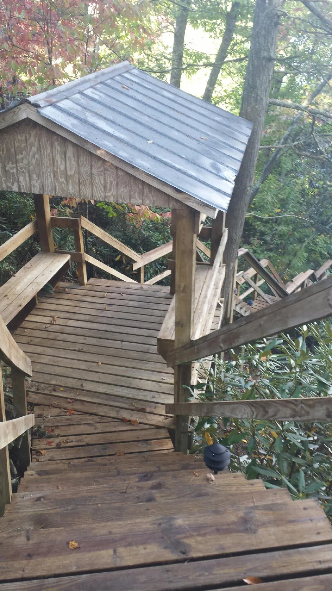 Metal roofed shelter over wooden steps on a wooded walkway — Skylight Repair & Installation work by our crew in Waukomis