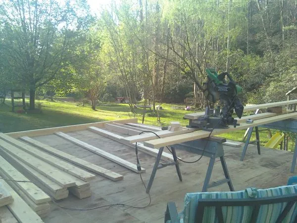 Miter saw and framing lumber on a deck under construction in Waukomis