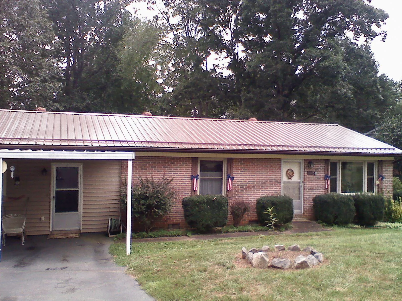 Bronze metal roof and carport on a brick ranch home — Roof Repair work by our crew in Waukomis