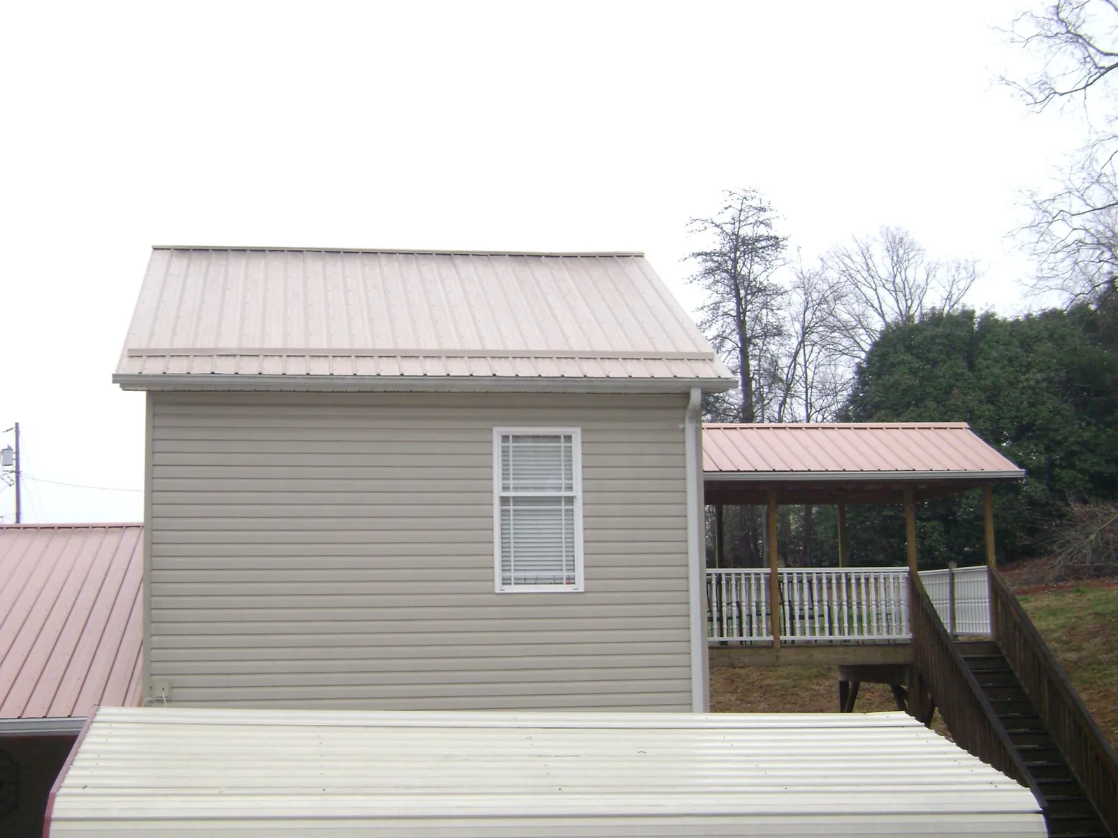 Tan metal roofs on a two story addition and attached porch, from a Roof Replacement job in Waukomis