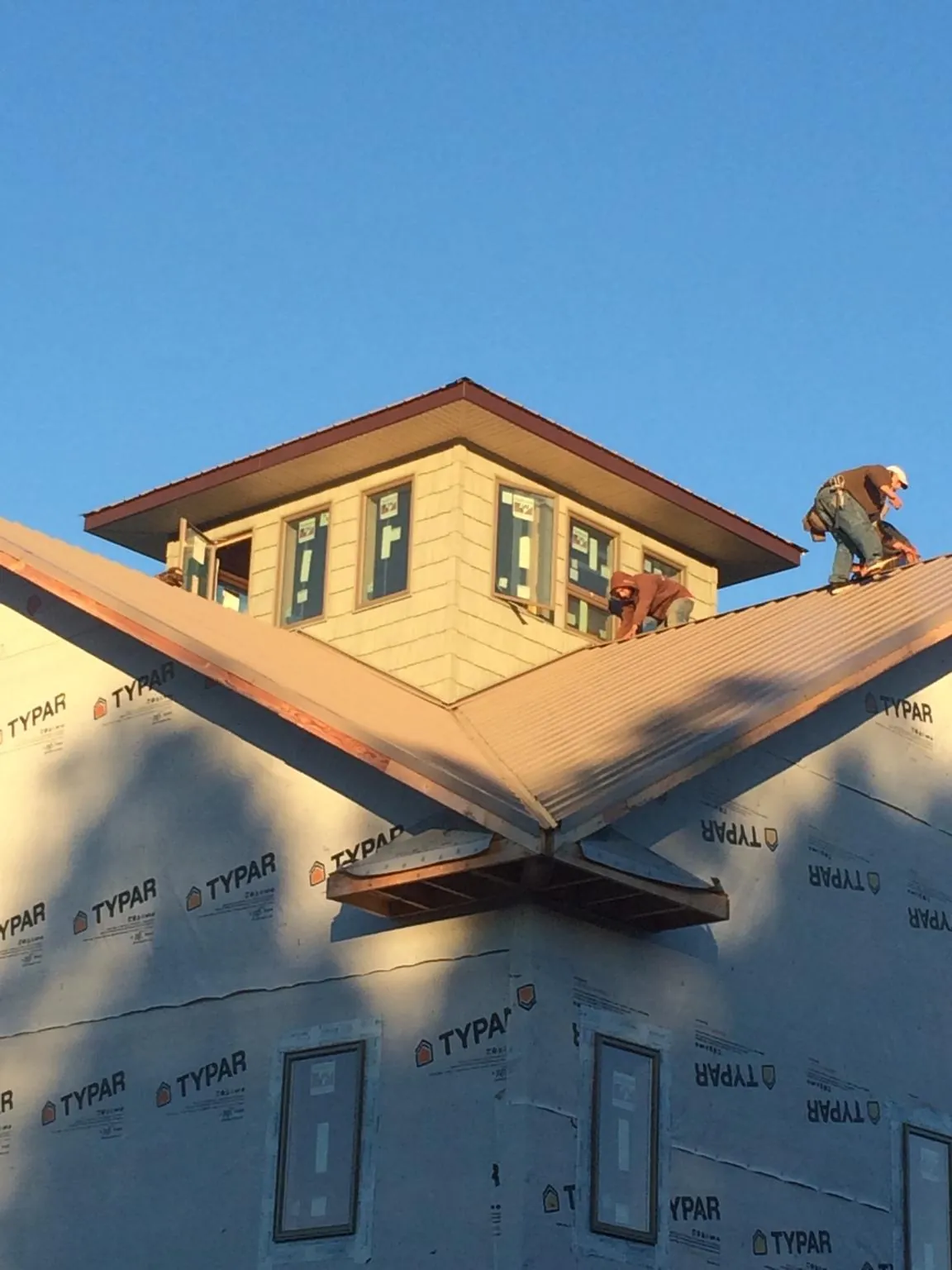 Roofers working around a rooftop cupola on a new metal roof at sunset — Roof Waterproofing in Waukomis by Roofing Brothers